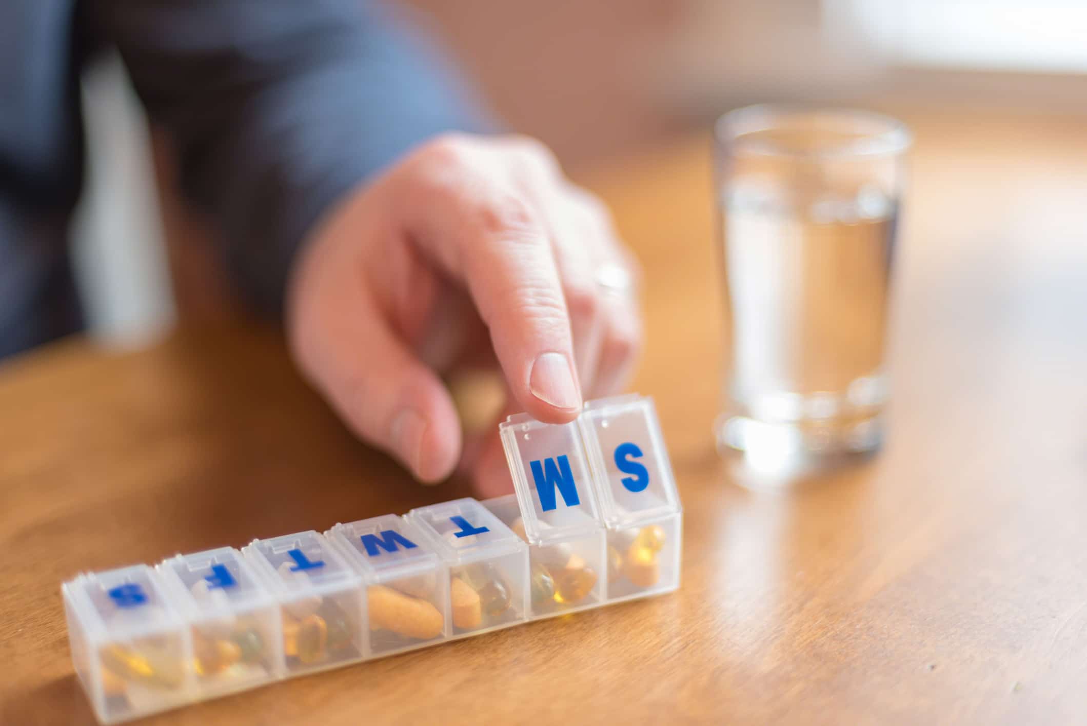 An older man using a pill organizer after following medication management tips.