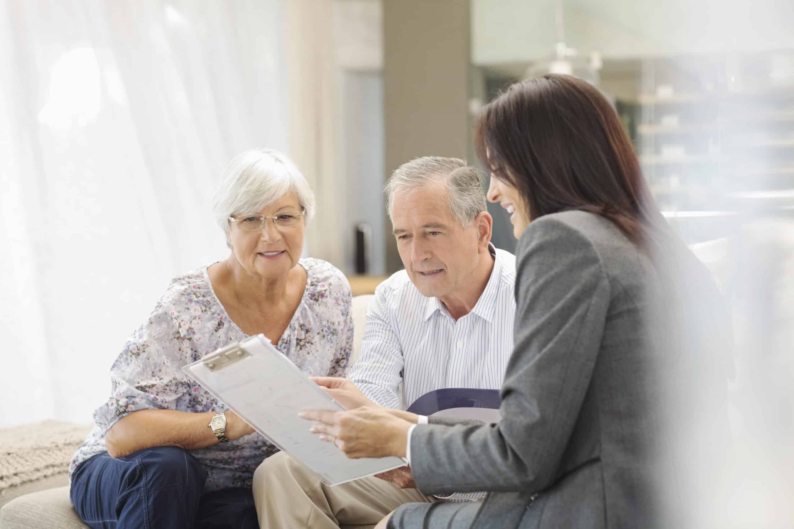 A caretaker and two older adults viewing a list of questions to ask when visiting a senior living community.